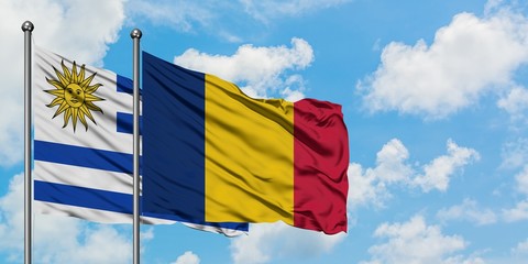 Uruguay and Chad flag waving in the wind against white cloudy blue sky together. Diplomacy concept, international relations.