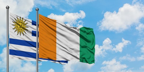 Uruguay and Cote D'Ivoire flag waving in the wind against white cloudy blue sky together. Diplomacy concept, international relations.