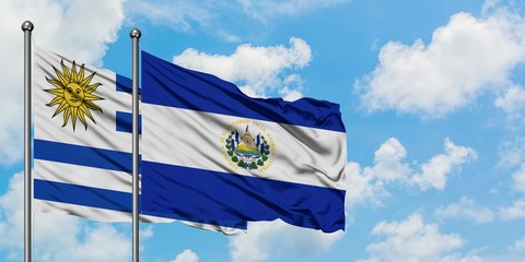 Uruguay and El Salvador flag waving in the wind against white cloudy blue sky together. Diplomacy concept, international relations.
