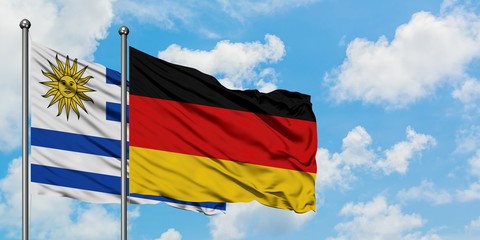 Uruguay and Germany flag waving in the wind against white cloudy blue sky together. Diplomacy concept, international relations.