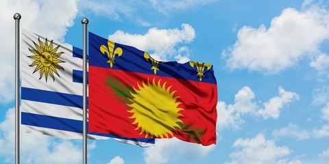 Uruguay and Guadeloupe flag waving in the wind against white cloudy blue sky together. Diplomacy concept, international relations.