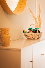 warm interior of a living room with a mirror and a desk with little lavender bags in a basket and dried reed.