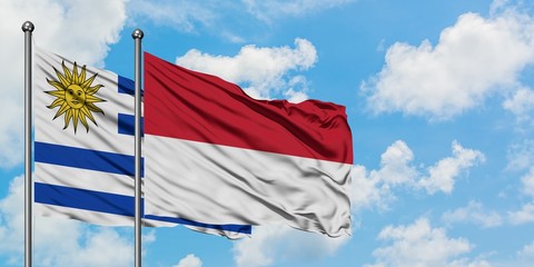 Uruguay and Indonesia flag waving in the wind against white cloudy blue sky together. Diplomacy concept, international relations.