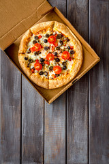 Pizza delivery. Italian food in box on dark wooden background top view copy space