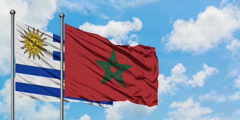 Uruguay and Morocco flag waving in the wind against white cloudy blue sky together. Diplomacy concept, international relations.