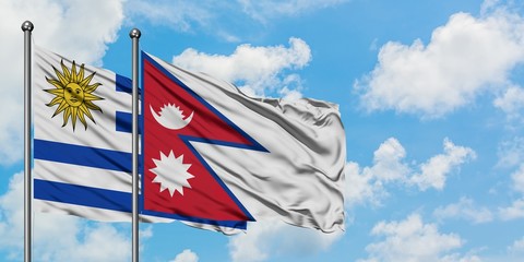Uruguay and Nepal flag waving in the wind against white cloudy blue sky together. Diplomacy concept, international relations.