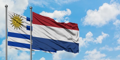 Uruguay and Netherlands flag waving in the wind against white cloudy blue sky together. Diplomacy concept, international relations.