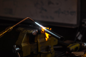 Worker welding and heating a metal bar motorcycle part using a machine. close-up.