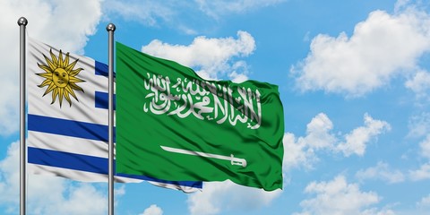 Uruguay and Saudi Arabia flag waving in the wind against white cloudy blue sky together. Diplomacy concept, international relations.