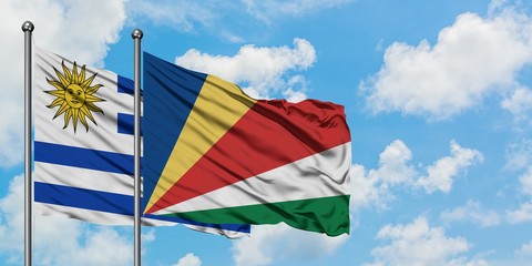Uruguay and Seychelles flag waving in the wind against white cloudy blue sky together. Diplomacy concept, international relations.