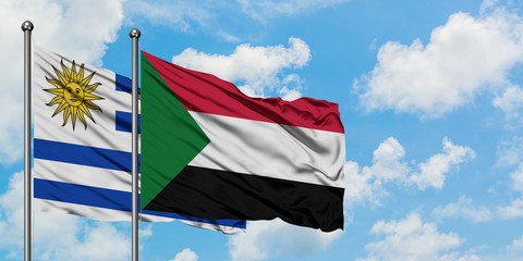Uruguay and Sudan flag waving in the wind against white cloudy blue sky together. Diplomacy concept, international relations.