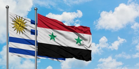 Uruguay and Syria flag waving in the wind against white cloudy blue sky together. Diplomacy...