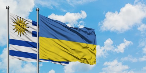 Uruguay and Ukraine flag waving in the wind against white cloudy blue sky together. Diplomacy concept, international relations.