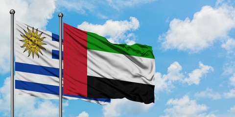 Uruguay and United Arab Emirates flag waving in the wind against white cloudy blue sky together....