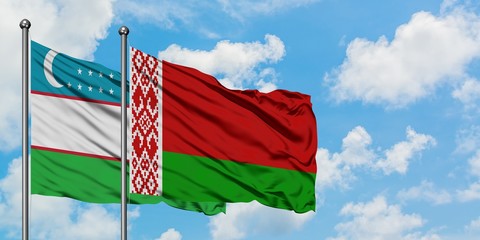 Uzbekistan and Belarus flag waving in the wind against white cloudy blue sky together. Diplomacy...