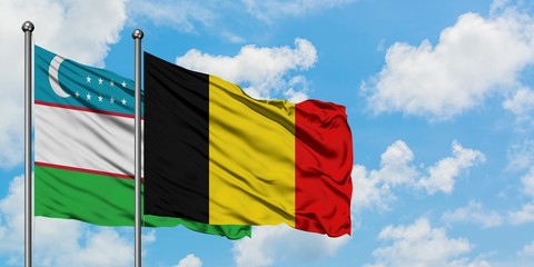 Uzbekistan and Belgium flag waving in the wind against white cloudy blue sky together. Diplomacy concept, international relations.