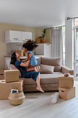 Fototapeta premium Mom and daughter multiraces move to a new apartment. Have fun jumping and playing on sofa.