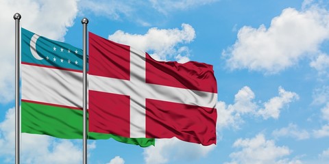 Uzbekistan and Denmark flag waving in the wind against white cloudy blue sky together. Diplomacy concept, international relations.