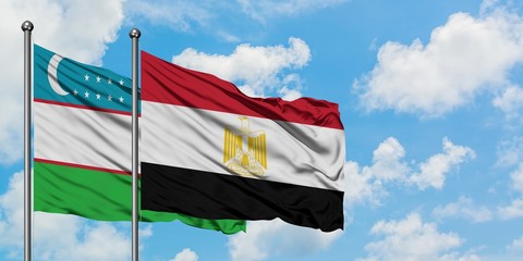 Uzbekistan and Egypt flag waving in the wind against white cloudy blue sky together. Diplomacy concept, international relations.