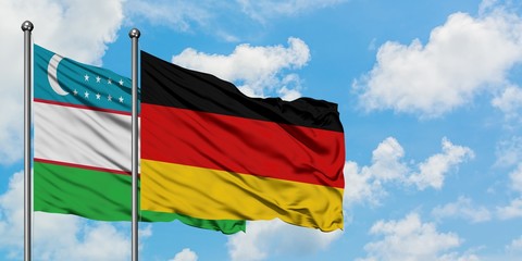 Uzbekistan and Germany flag waving in the wind against white cloudy blue sky together. Diplomacy concept, international relations.