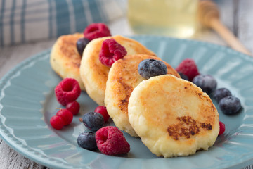Cottage cheese pancakes with sour cream and tea. Gourmet Breakfast - Cottage cheese pancakes, syrniki, curd fritters in a white plate. Russian syrniki or sirniki, cottage cheese fritters.