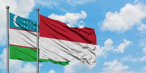 Uzbekistan and Indonesia flag waving in the wind against white cloudy blue sky together. Diplomacy concept, international relations.