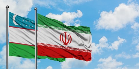 Uzbekistan and Iran flag waving in the wind against white cloudy blue sky together. Diplomacy concept, international relations.