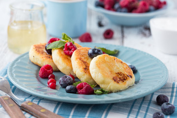 Cottage cheese pancakes with sour cream and tea. Gourmet Breakfast - Cottage cheese pancakes, syrniki, curd fritters in a white plate. Russian syrniki or sirniki, cottage cheese fritters.