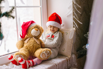 happy child girl sitting back in the winter window Christmas