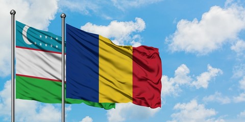 Uzbekistan and Romania flag waving in the wind against white cloudy blue sky together. Diplomacy...