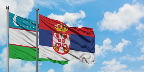 Uzbekistan and Serbia flag waving in the wind against white cloudy blue sky together. Diplomacy concept, international relations.