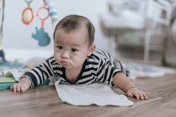 Adorable Asian baby boy learning to crawl and playing on the floor at home