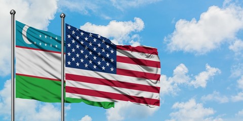 Uzbekistan and United States flag waving in the wind against white cloudy blue sky together. Diplomacy concept, international relations.