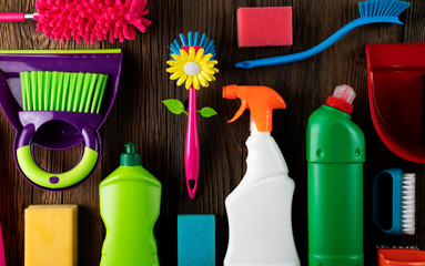 Autumn house cleaning theme.  Colorful cleaning products on rustic wooden table. Top view shot. Place for typography.