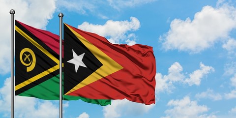 Vanuatu and East Timor flag waving in the wind against white cloudy blue sky together. Diplomacy concept, international relations.