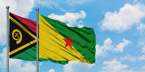 Vanuatu and French Guiana flag waving in the wind against white cloudy blue sky together. Diplomacy...
