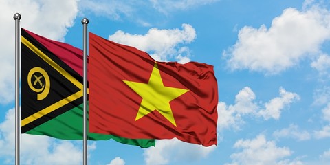 Vanuatu and Vietnam flag waving in the wind against white cloudy blue sky together. Diplomacy...