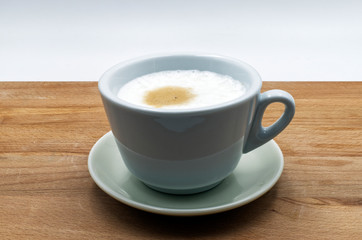 Italian cappuccino in a ceramic cup, wooden table, white background
