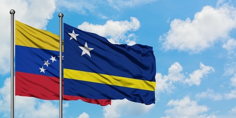 Venezuela and Curacao flag waving in the wind against white cloudy blue sky together. Diplomacy concept, international relations.