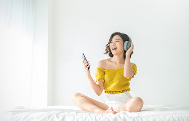 Portrait of beautiful asian woman listen to music sing and dance from headphone in bedroom. Smile...