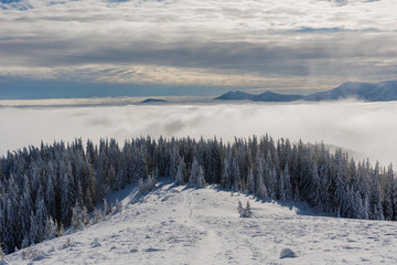 Beautiful scenery with winter snow-capped mountains, with fogs and contrasting snow structure and red tourist tent in the foreground, in locations in the Ukrainian Carpathians.