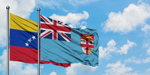 Venezuela and Fiji flag waving in the wind against white cloudy blue sky together. Diplomacy concept, international relations.