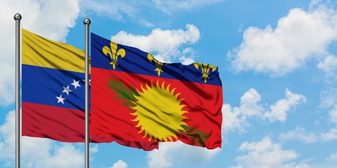 Venezuela and Guadeloupe flag waving in the wind against white cloudy blue sky together. Diplomacy...