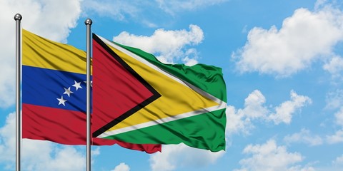 Venezuela and Guyana flag waving in the wind against white cloudy blue sky together. Diplomacy...