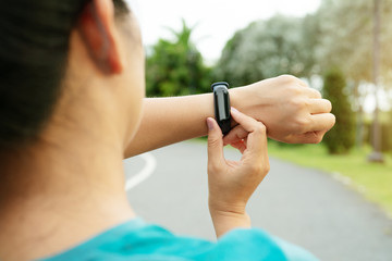 Fototapeta na wymiar fitness woman runner setting up smart watch before running. Outdoor exercise activities