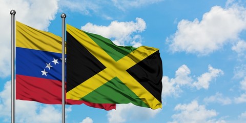 Venezuela and Jamaica flag waving in the wind against white cloudy blue sky together. Diplomacy concept, international relations.