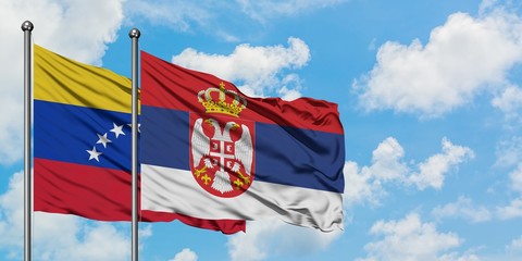 Venezuela and Serbia flag waving in the wind against white cloudy blue sky together. Diplomacy concept, international relations.