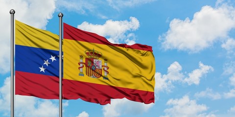Venezuela and Spain flag waving in the wind against white cloudy blue sky together. Diplomacy concept, international relations.