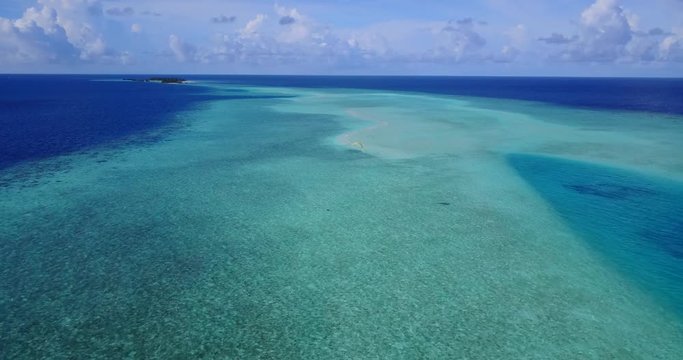 Adventurous tourists flying over large turquoise lagoon by powered parachute enjoying freedom of endless ocean in Malaysia