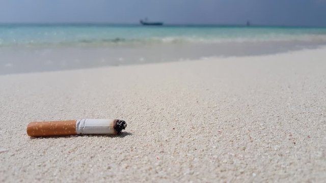 Close Up Of Cigarette Bud On White Sand Beach, unhealthy lifestyle and addiction concept